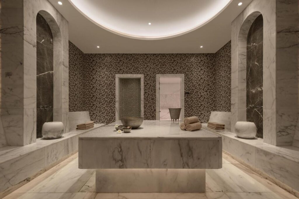 Sala spa w JAZ Elite Riviera wyłożona marmurem, z szerokim kamiennym stołem pośrodku