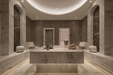 Sala spa w JAZ Elite Riviera wyłożona marmurem, z szerokim kamiennym stołem pośrodku