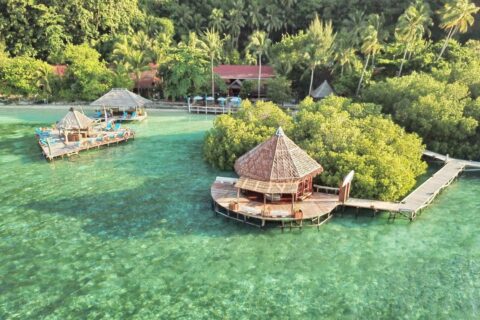 Raja Ampat Dive Lodge z lotu ptaka: pomosty na palach i czerwone dachy pod palmami