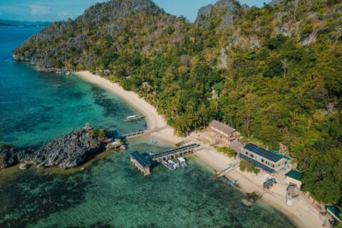 Sangat Island Dive Resort z lotu ptaka: plaża, pomost i łodzie u stóp klifów