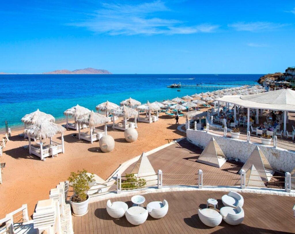 Plaża Sunrise Arabian Beach Resort ze słomianymi parasolami i pomostem, naprzeciw wyspy Tiran