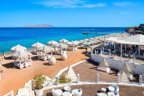 Plaża Sunrise Arabian Beach Resort ze słomianymi parasolami i pomostem, naprzeciw wyspy Tiran